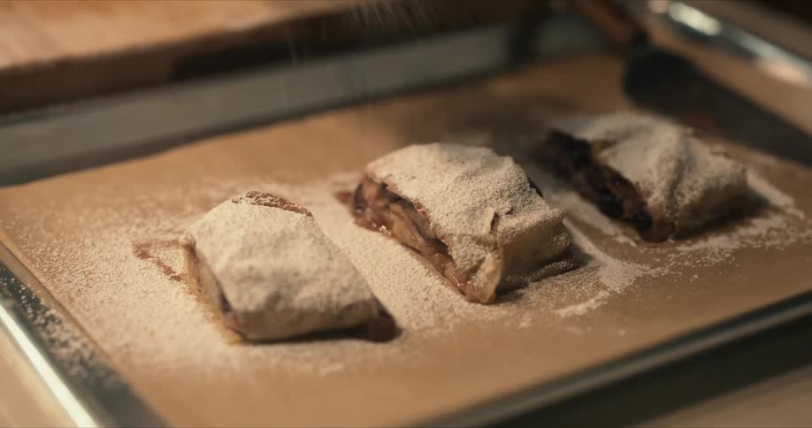 Powdered sugar is sprinkled on a baked dessert