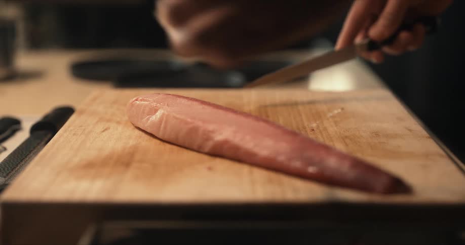 A person is cutting raw fish