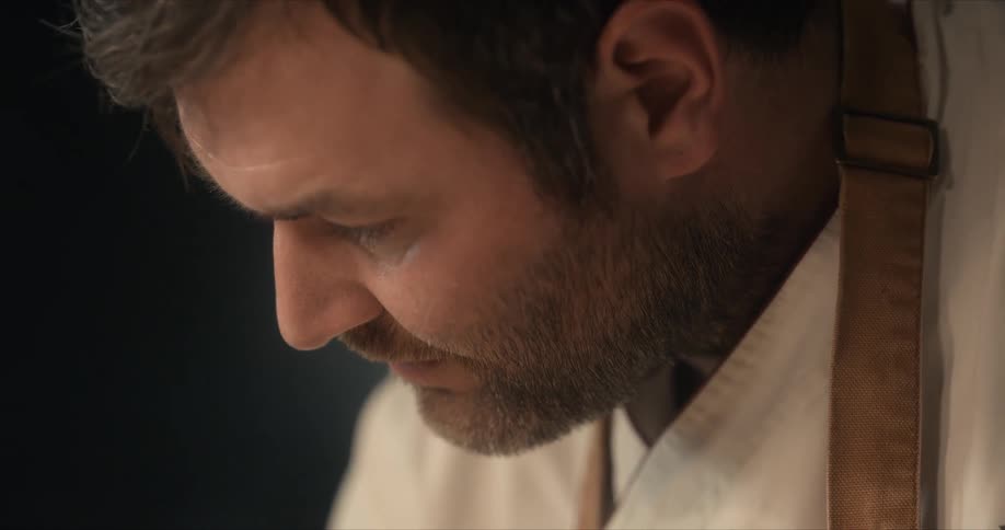 Light is shining on a man's face as he is looking down at something