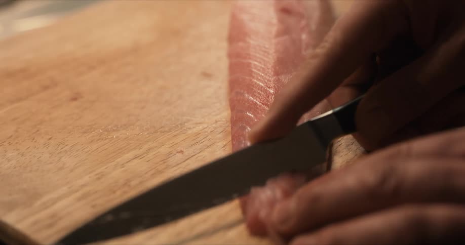 A person cuts raw fish with a knife