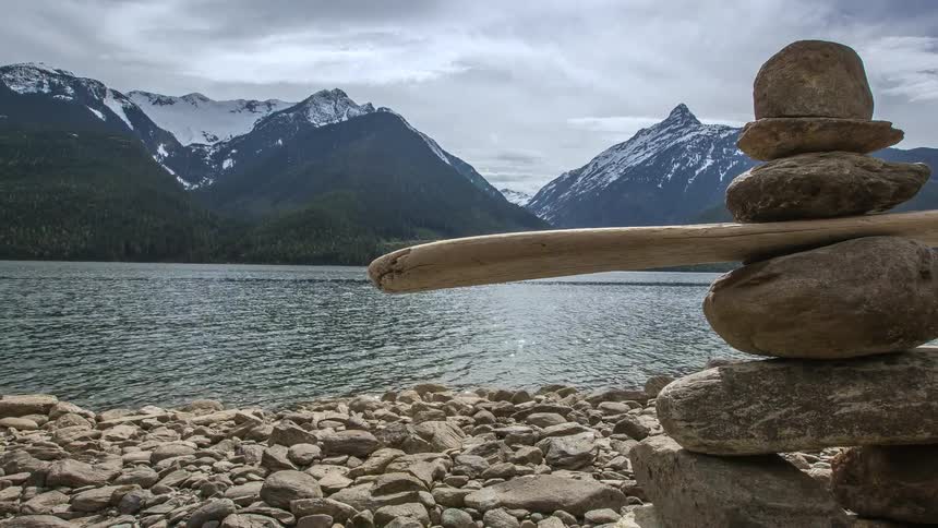 Time lapse of a lake before a mountain with rocks stacked by the shore