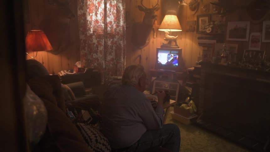 A man is sitting in his living room watching television