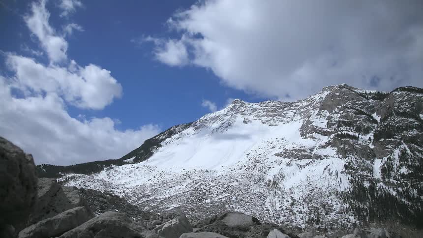 Clouds pass over a snowy mountain