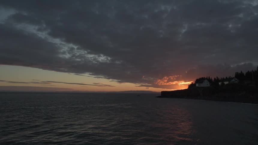 A coastline at sunset has heavy clouds above