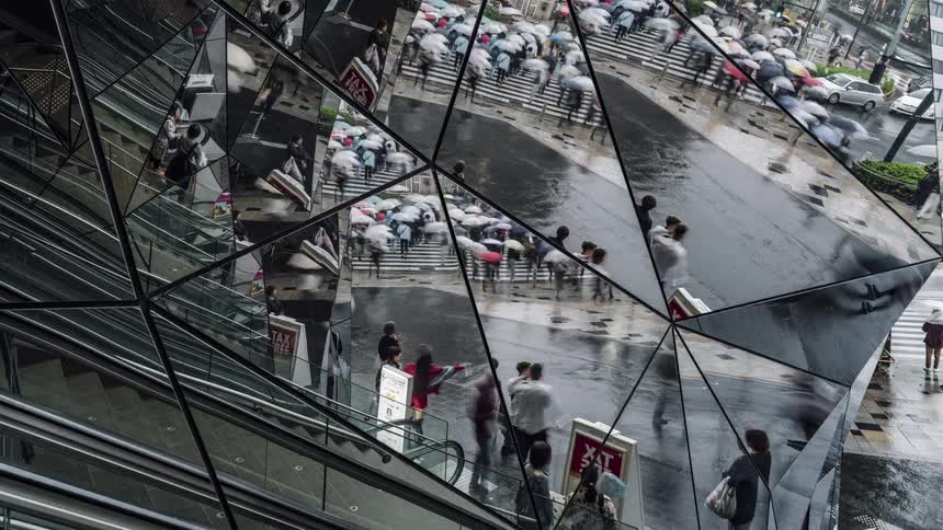 Pedestrians cross the street in the reflection of the mirrors