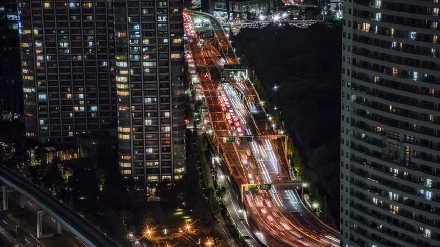 Traffic travels along a busy freeway through a metropolis at night