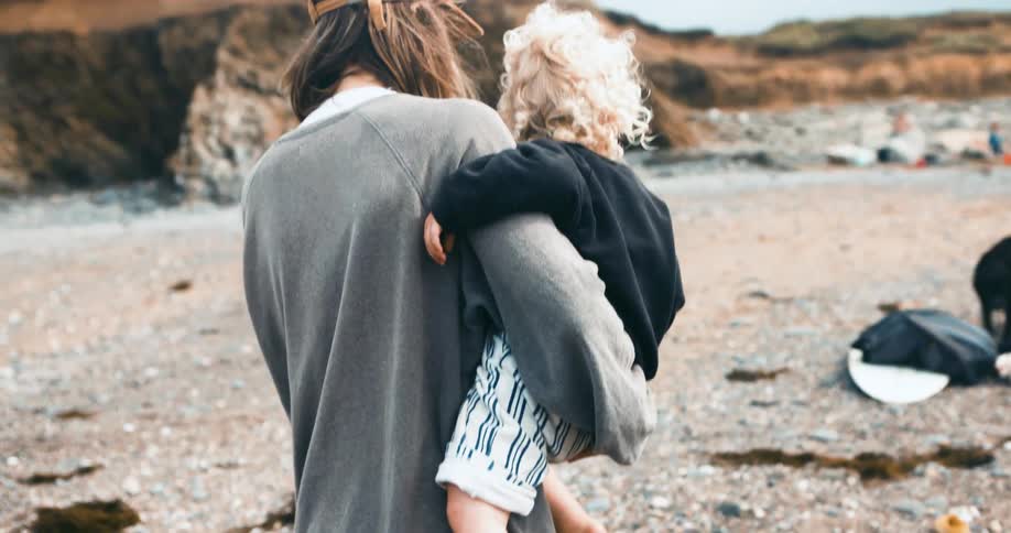 A woman carries her child in the sand