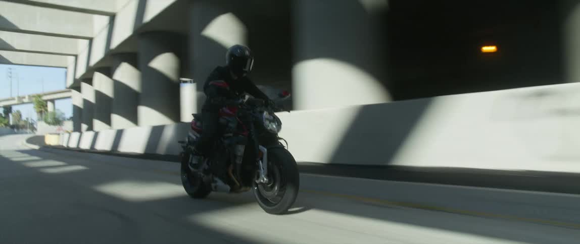 A motorcyclist rides a motorcycle along a freeway during the day