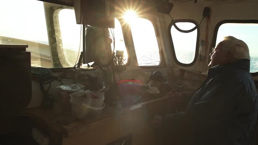 A man is sitting in a ship steering on a sunny day