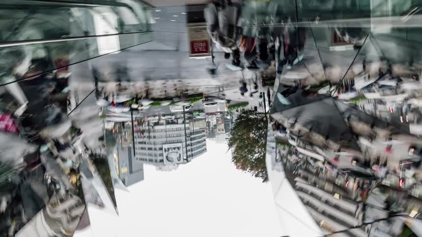 Busy crowds walk past reflective skyscrapers downtown