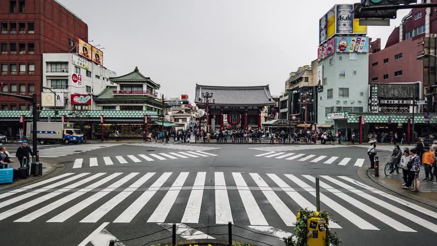 Pedestrians and vehicles crossing the intersection in a downtown area in a city in the orient
