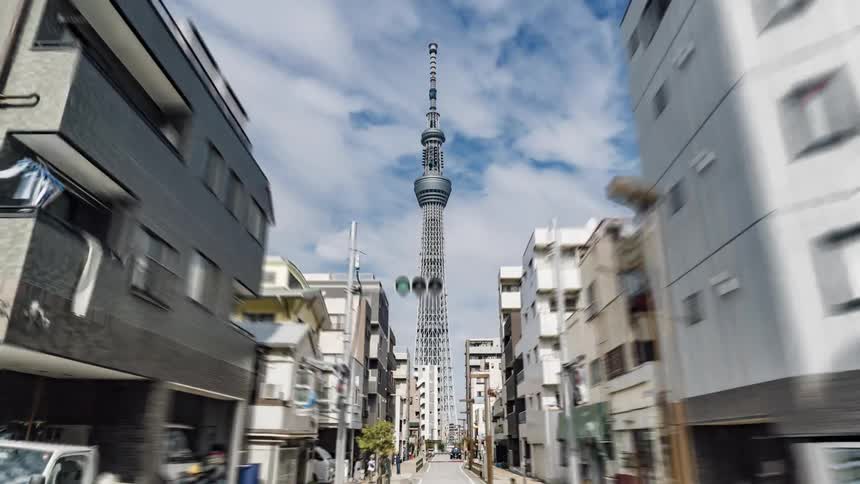 Vehicles and pedestrians travel on the city street that leads to a tall tower