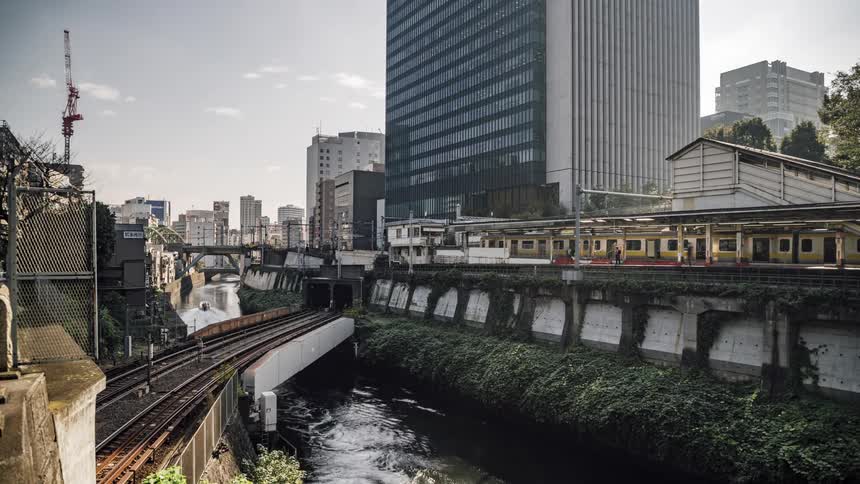 A train station beside a river in a metropolis during the day