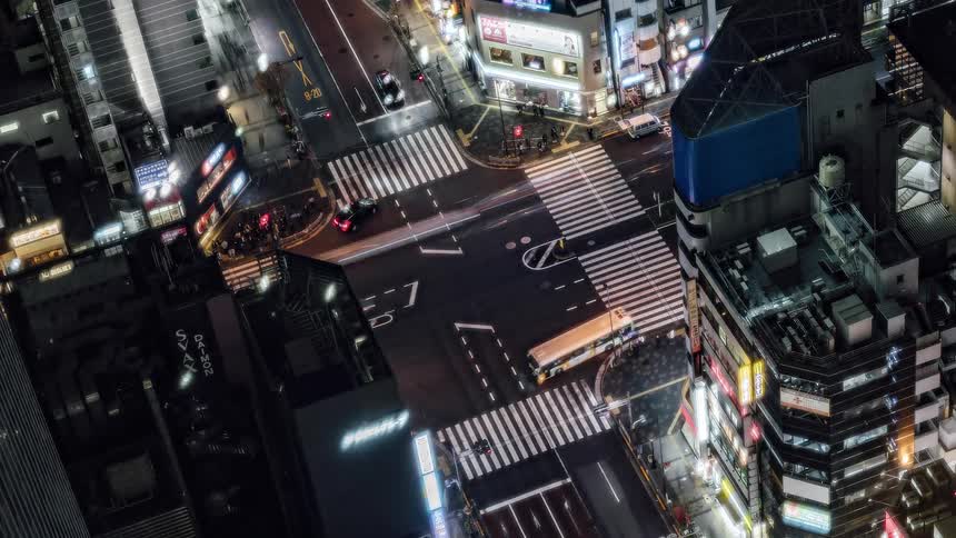 Traffic moves through a busy city street at night
