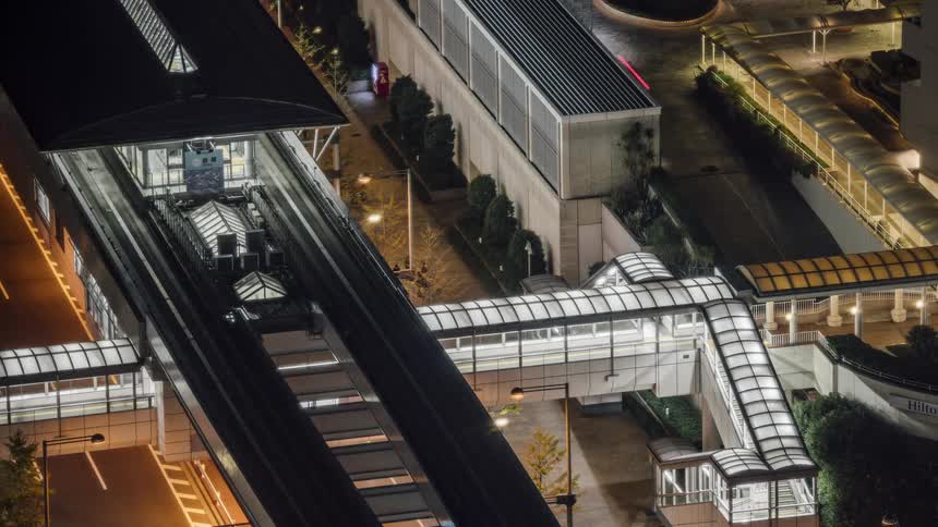 People walk down lit pedestrian bridges at night