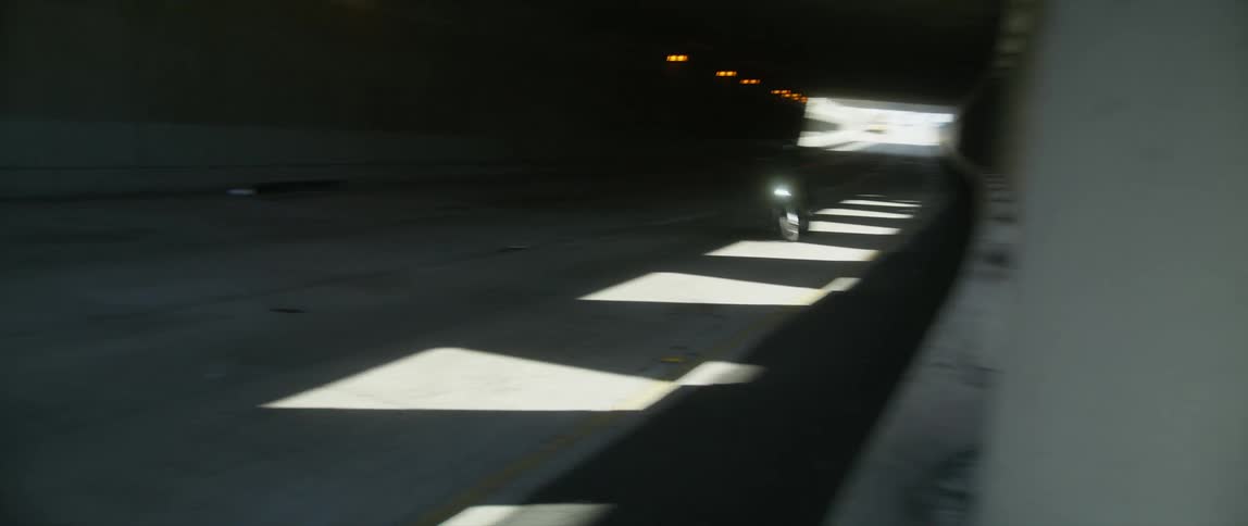 Motorcycle rides through the dark tunnel into the sun