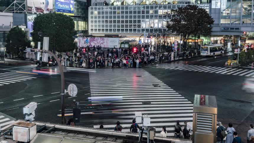 Vehicles travel through an intersection then stop to let the pedestrians cross in the city