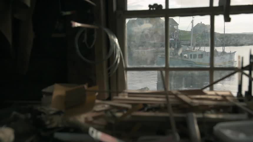 A boat is shown floating on a lake through a shop window