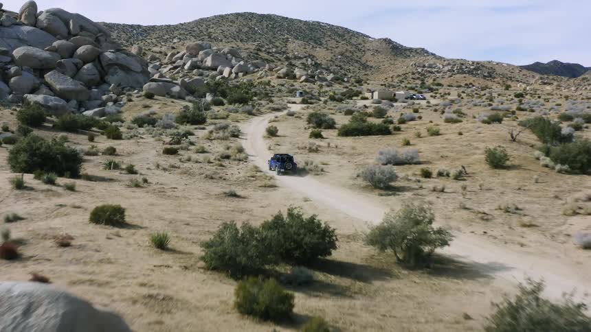 A vehicle drives on the trail through the desert