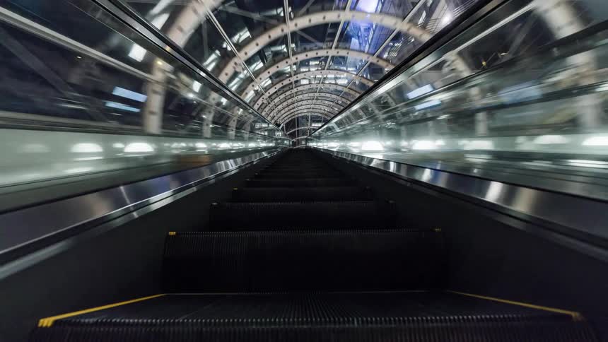 Pedestrian walks towards a tunnel that leads to an escalator in the city at night