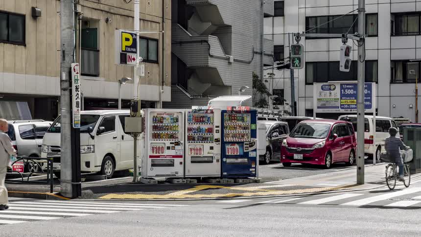Vending machines in a parking lot on the corner of a busy intersection in a metropolis during the day