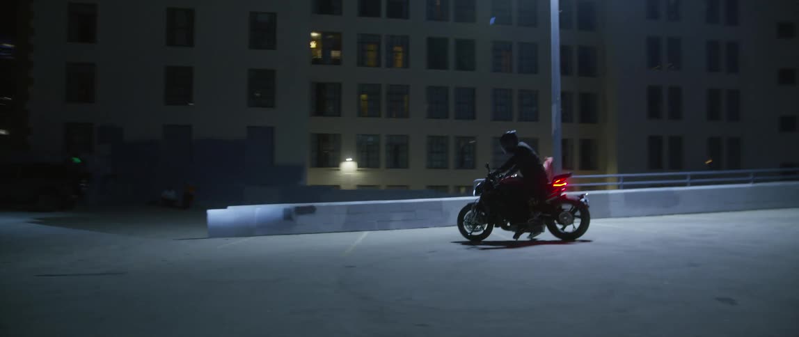 A rider wearing helmet with visor runs to their motorcycle jumps on and drives off