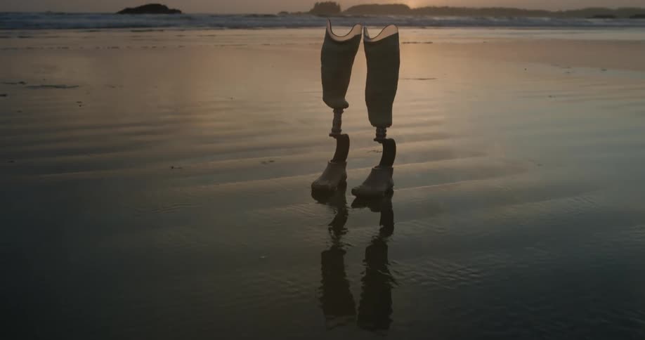 A set of prosthetic legs are standing in the sand