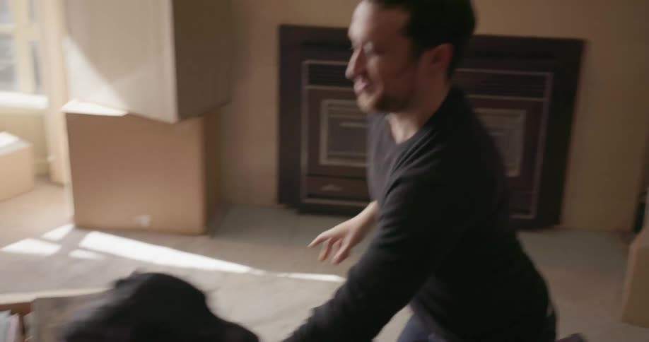 A man is playing with his dog on the floor of his living room