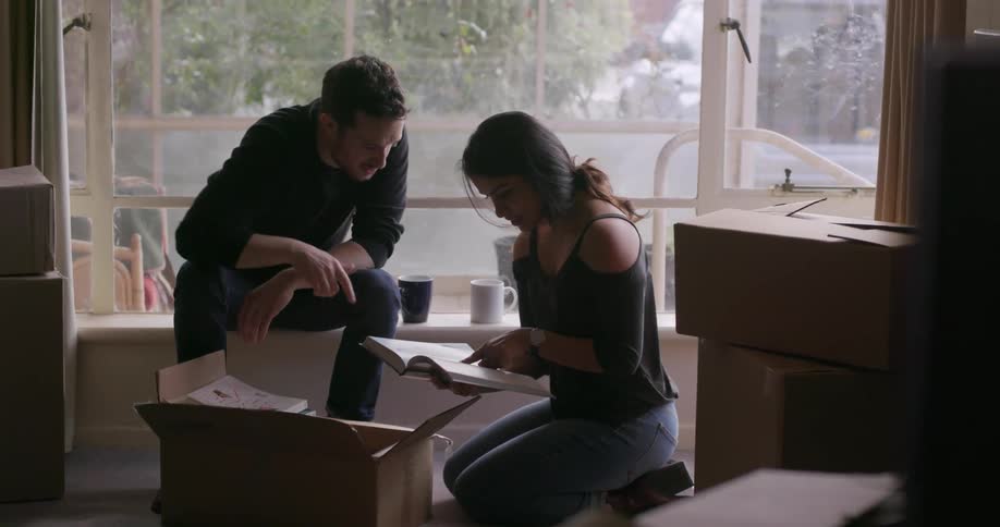 A man and woman are looking at a book with an open box in front of them