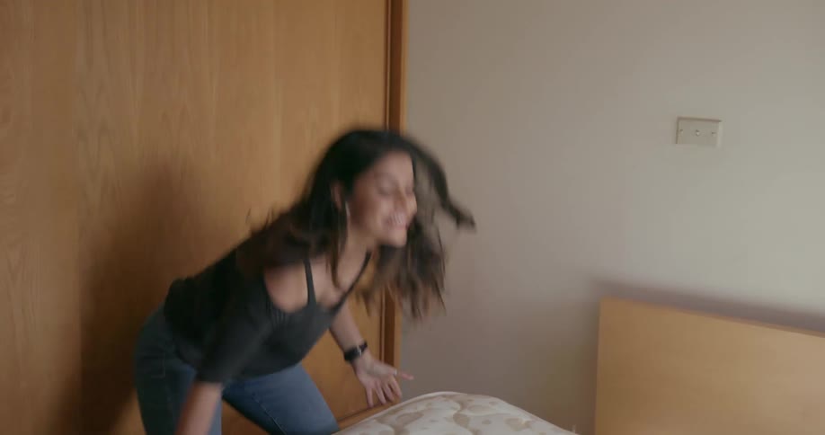 A man and dog jump onto a bed as he and his female companion finish putting it together