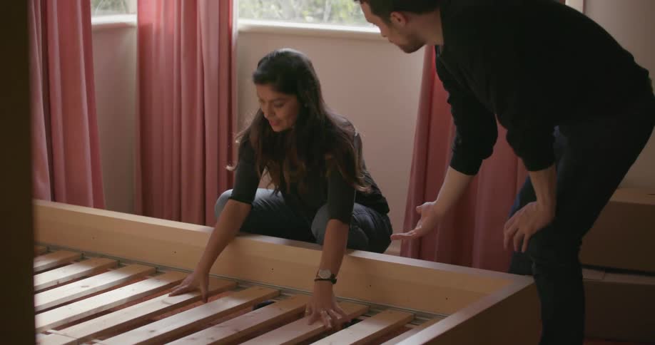 A man and woman put together a bed frame