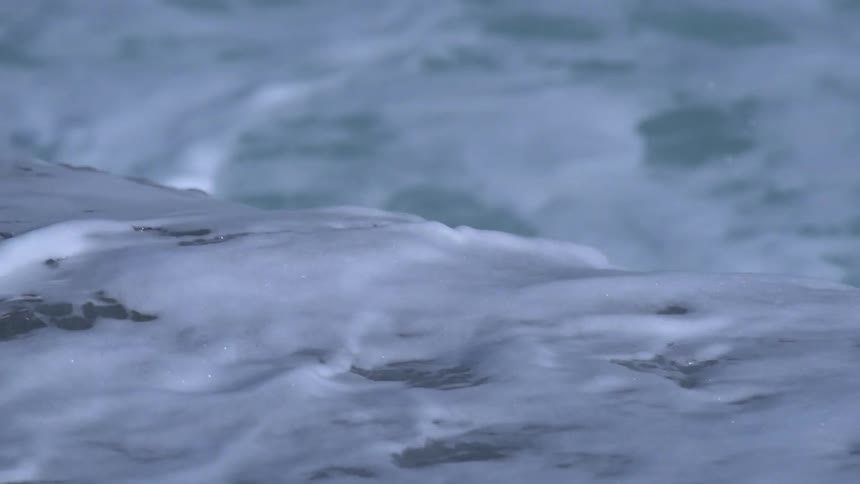 Ocean waves recede and then splash back up onto the rocks