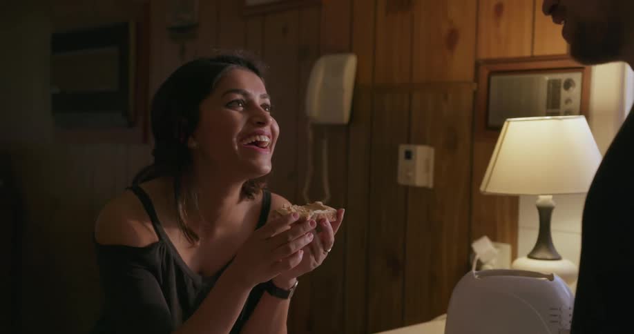 A man and woman eat breakfast at a kitchen counter