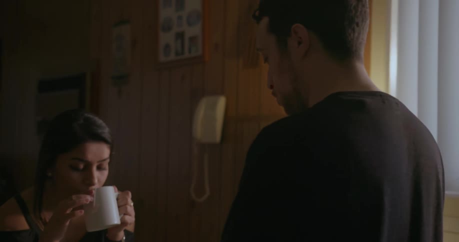 A man and woman talk at a kitchen counter