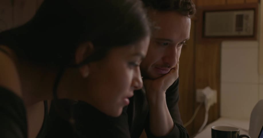 A man and woman are looking at a laptop