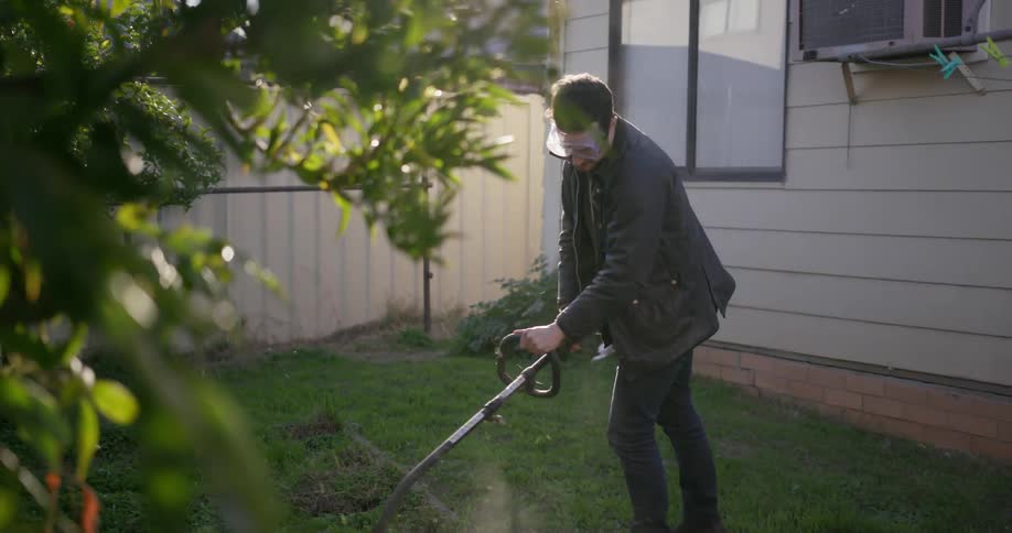 A man is using a grass trimmer on his lawn