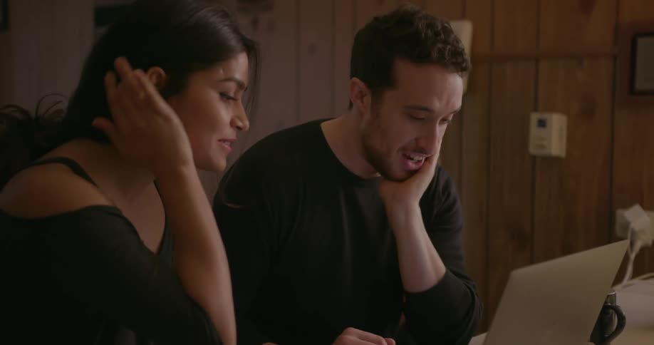 Man and woman smile and talk while looking at a laptop
