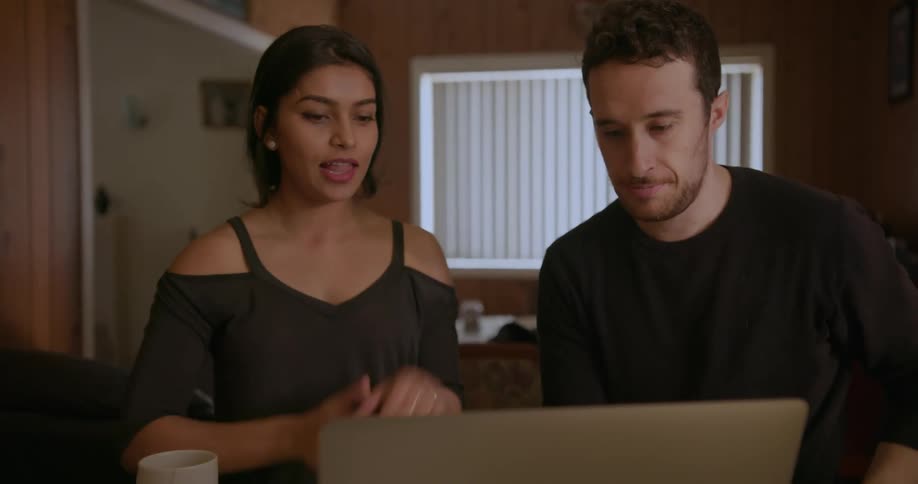 A man and woman speaking in front of a laptop