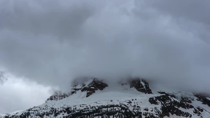 Clouds move fast over a snow covered mountain