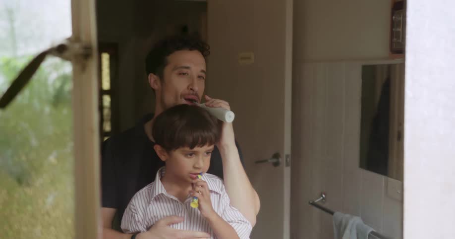 A father and son are brushing their teeth together