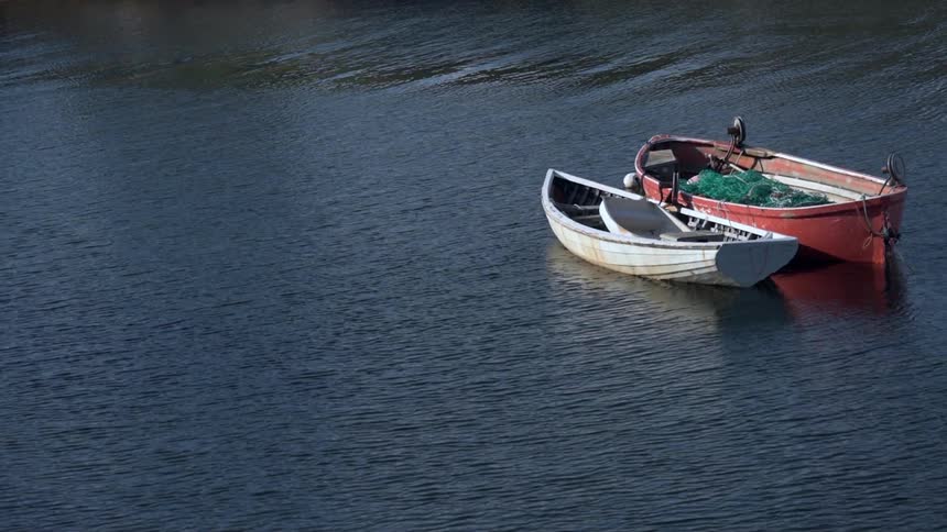 Two small boats float on a body of water