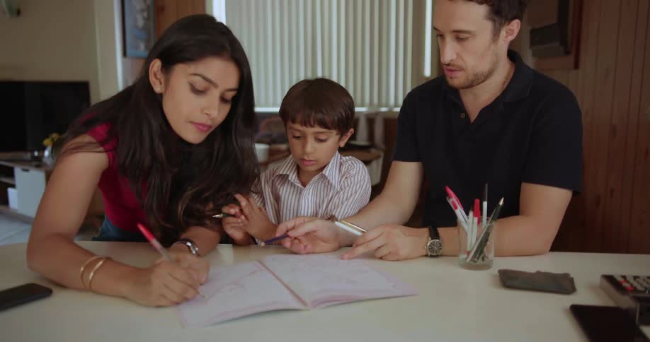 A man and woman are helping a small child with their school work