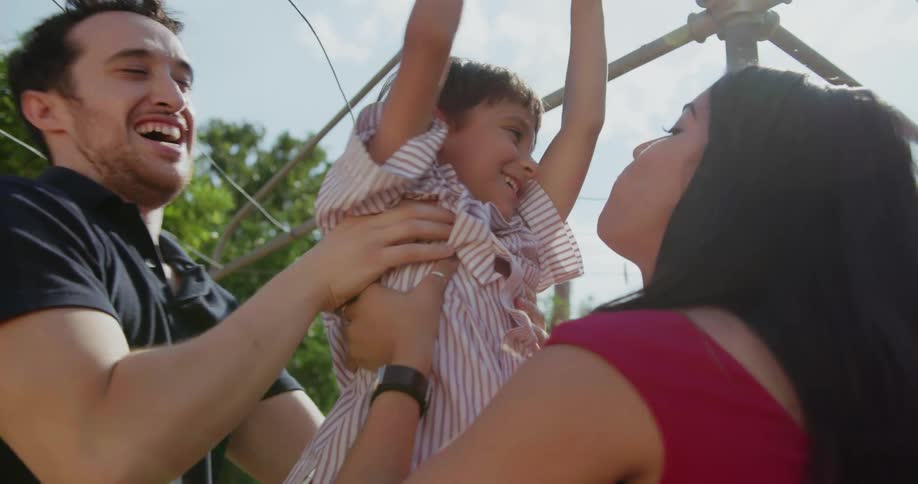 Parents grab their son who is holding on to the clothes line in the yard