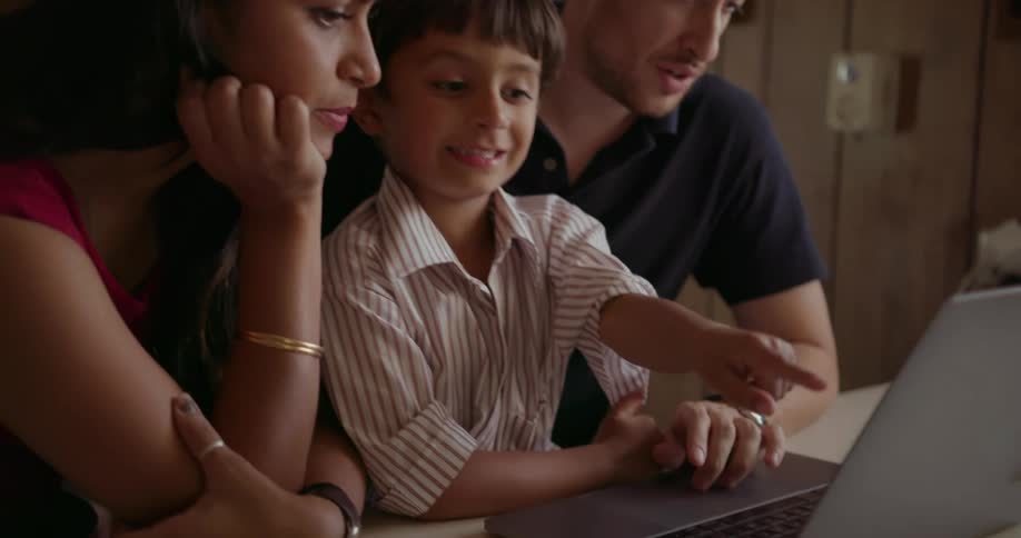 A mother, father and child use a laptop together