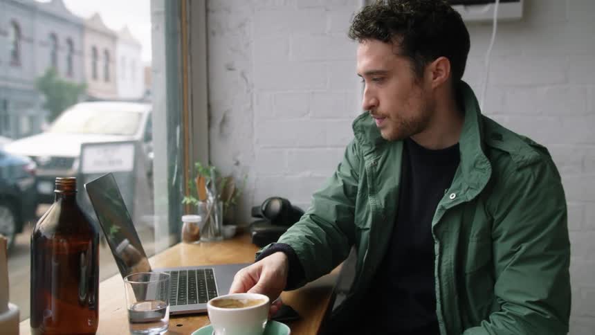 A man uses a laptop at a coffee shop