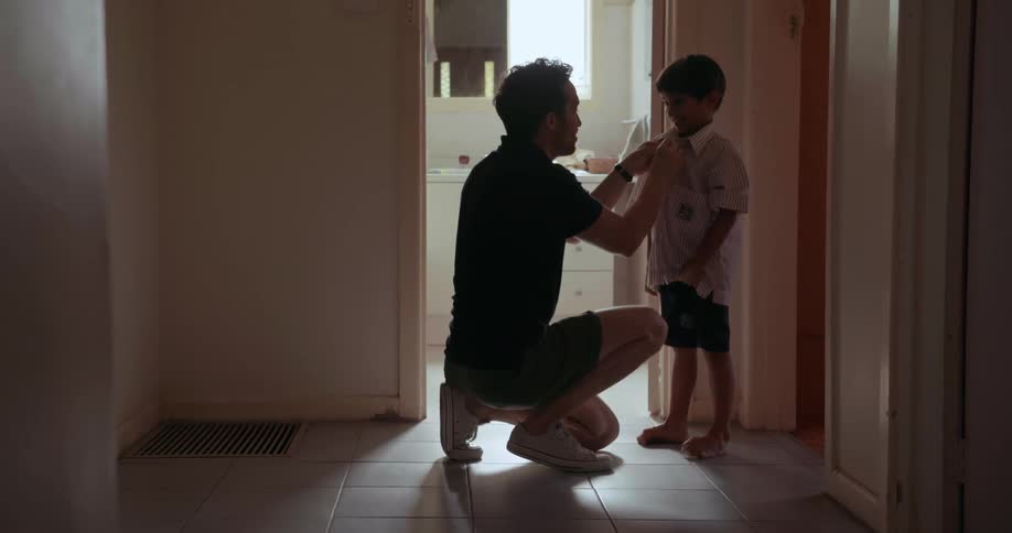 A man helps a young boy dress