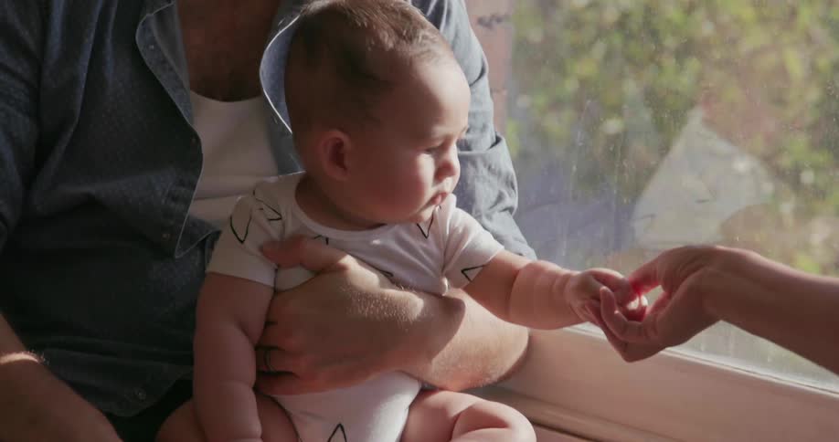 Man holds baby in front of a window