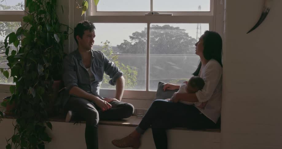 Man and woman talk as they sit on a window ledge