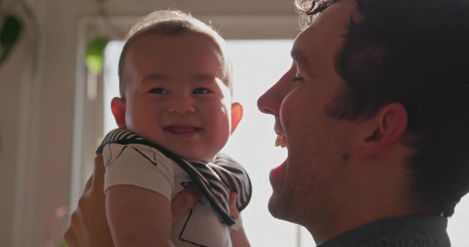 A man is kissing the face of a small baby