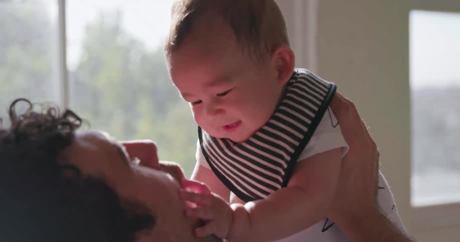 A baby laughs and touches his dad's face